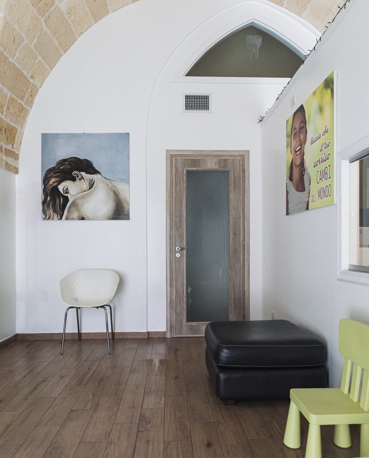 La sala d’attesa dello Studio Dentistico San Camillo: divano, quadro e volta in pietra a vista